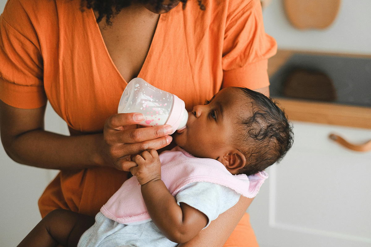 Close-up photo of a woman feeding a baby.