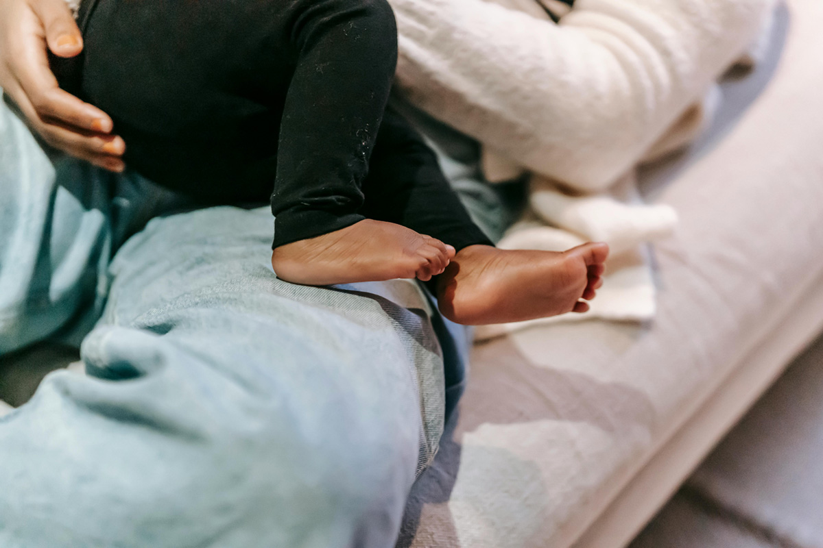 Mother lying on a sofa with her barefoot baby.